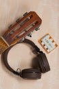 Fragment of acoustic guitar and tuning fork. Nearby are wireless headphones. Against a background painted in white and beige Royalty Free Stock Photo