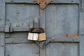 Fragment of ancient cracked peeling and decayed monastery gates with rusty forged overlays and modern padlocks.