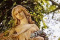 A fragment of ancient sculpture angel in a golden glow in the old cemetery.