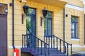 A fragment of a beautiful entrance of the facade of the house with wooden railings on the stairs and openwork lanterns in the old Royalty Free Stock Photo