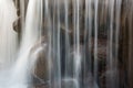 fragment of a beautiful waterfall with large stones with vertical blurry streams and splashes. close-up side view