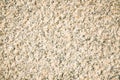 Fragment of a beige granite facing slab. Untreated scabrous stone surface of natural beige granite.