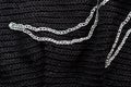 Fragment of a black crocheted bag with abstract embroidery with silver thread close-up. Top view. Hand made concept
