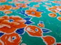 Fragment of bright grass green colorful vintage textile pattern with big orange flowers useful as background or fabric sample