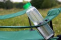 Fragment of a camping chair with a bottle of water and a bouquet. Stands on the grass of a summer meadow Royalty Free Stock Photo