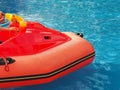 Fragment of a children's red inflatable boat floating in a blue outdoor pool Royalty Free Stock Photo