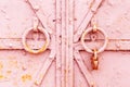 Fragment of a closed old metal door or gate with round knockers and a rusty padlock. Closeup shabby worn texture of iron