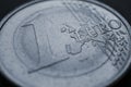 Fragment of a coin of 1 one euro close up. In focus inscription with the name of the Eurozone currency. Dark generic gray tinted Royalty Free Stock Photo