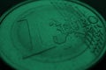 Fragment of a coin of 1 one euro close up. In focus inscription with the name of the Eurozone currency. Dark green tinted