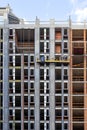 Fragment of the construction of a residential building using a construction cradle on a sunny day