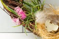 A fragment of a decorative spring wreath made of branches, flowers, a bird's nest with quail eggs and feathers