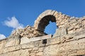 Fragment of a destroyed antique fortress wall with arch against the sky