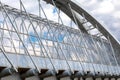 Fragment of an elevated pedestrian crosswalk. Arched support beam of a suspended pedestrian bridge with mounting elements against Royalty Free Stock Photo