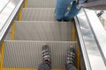 Fragment of an escalator with people going up. Unrecognizable person. Male feet on the escalator, top view. Escalator steps in the