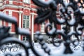 Fragment of the facade of a historic building through snow-covered courtyard gates from metal Royalty Free Stock Photo