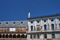 Fragment of the facade of a historic tenement house against the background of the colonnade of the medieval Palazzo della Ragione