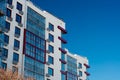 Fragment of the facade of a modern apartment building, white walls and glass balconies against the blue sky Royalty Free Stock Photo