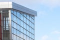 A fragment of the facade of a modern building made of glass and concrete against a blue sky. Royalty Free Stock Photo