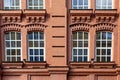 Fragment of facade of old classic red brick building with four large windows with white frames Royalty Free Stock Photo