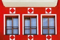 fragment of the facade of red building with with three windows and decorative elements Royalty Free Stock Photo
