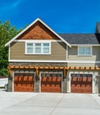 Fragment of farmer`s house with three garage doors and concrete driveway