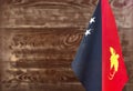 Fragment of the flag of Papua New Guinea in the foreground blurred wooden background copy space