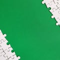 Fragment of a folded white jigsaw puzzle on the background of a green plastic surface. Texture photo with copy space for text