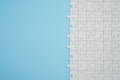 Fragment of a folded white jigsaw puzzle and a pile of uncombed puzzle elements against the background of a blue surface Royalty Free Stock Photo