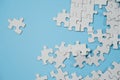 Fragment of a folded white jigsaw puzzle and a pile of uncombed puzzle elements against the background of a blue surface Royalty Free Stock Photo