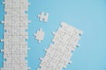 Fragment of a folded white jigsaw puzzle and a pile of uncombed puzzle elements against the background of a blue surface Royalty Free Stock Photo