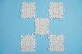 Fragment of a folded white jigsaw puzzle and a pile of uncombed puzzle elements against the background of a blue surface Royalty Free Stock Photo