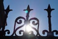 Fragment of a forged fence against the background of the sun and clear sky