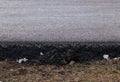 Fragment of freshly laid black asphalt on a cushion of rubble. Modern technology of solid pavement for vehicles and pedestrians. Royalty Free Stock Photo