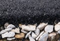 Fragment of freshly laid black asphalt on a cushion of rubble. Modern technology of solid pavement for vehicles and pedestrians. Royalty Free Stock Photo