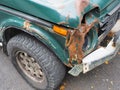 Fragment of a green car with a broken rusty front bent bumper and no headlight Royalty Free Stock Photo