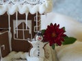 Fragment house, gingerbread snowman with red flower in front of a gingerbread house