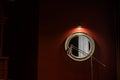 Fragment of the interior in a dark manner: a round mirror in a massive frame and a floor lamp. Royalty Free Stock Photo