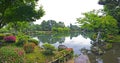 Fragment of japanese garden with stone lantern and big mossy rocks standing in the pond Royalty Free Stock Photo