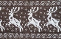 Fragment of a knitted fabric of handkerchief hand-knitted brown wool. Figure winter Christmas theme. White deer. View from above.