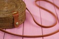 Fragment ladies handbag braided with brown strap on a pink background.