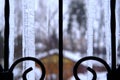 Fragment of large icicles behind a cast-iron grate against a blurred background. Close-up. Selective focus Royalty Free Stock Photo