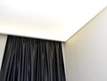 Fragment of the lit stretch ceiling and black silk portiere Royalty Free Stock Photo