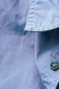 Fragment of men`s shirt collar button made from pure organic delicate blue gray cotton. Menswear fashion clothing design sewing