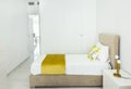 Fragment of modern bedroom in minimalist white and yellow interior design style with built-in closet. Bed with pillows duvet