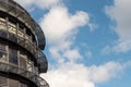 Fragment of modern building with metal and glass elements against blue cloudy sky. Round shape of the building. Advanced Royalty Free Stock Photo