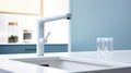 Fragment of a modern luxury kitchen with light blue wall and window on the background. White stone countertop with built Royalty Free Stock Photo