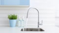 Fragment of a modern luxury kitchen with white backsplash on the background. White countertop with built-in sink, chrome