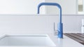 Fragment of a modern luxury white kitchen. Countertop with built-in sink, blue faucet. White tile backsplash. Close-up Royalty Free Stock Photo