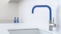 Fragment of a modern luxury white kitchen. Countertop with built-in sink, blue faucet. White tile backsplash. Close-up Royalty Free Stock Photo