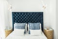 Fragment of modern master bedroom in minimalist white and blue interior design style. Bed with pillows duvet illumination lamps Royalty Free Stock Photo